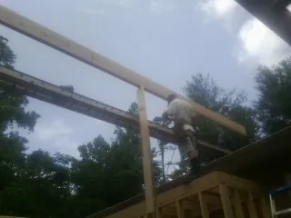 Carpenter setting a ridge beam over a new addition frame — Ice Dam Removal by Roofing Brothers in Penhook