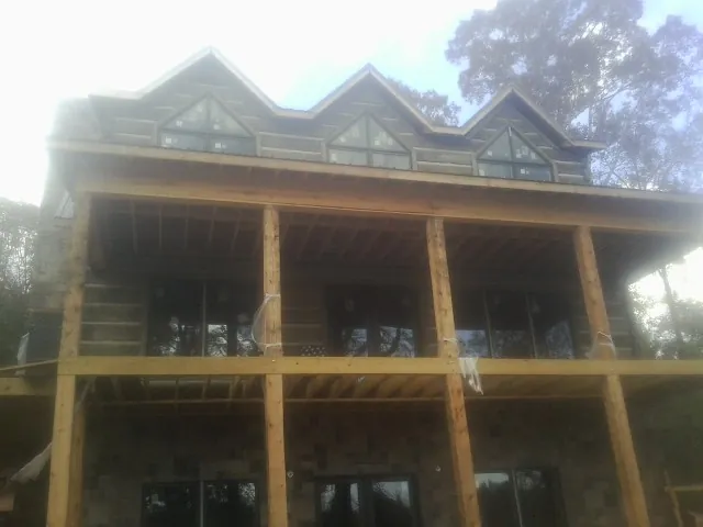 Dormers and porch framing on a large log home under construction — Roof Coating work by our crew in Penhook
