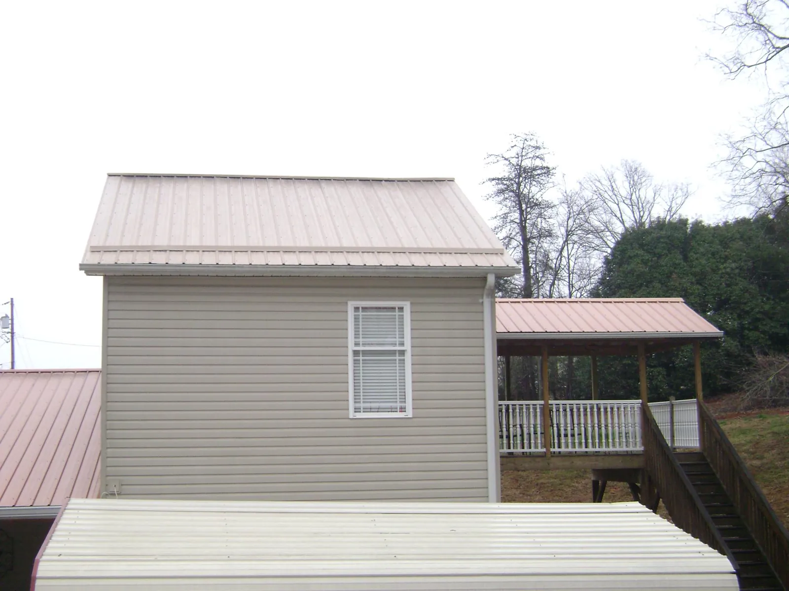 Tan metal roofs on a two story addition and attached porch, from a Roof Replacement job in Penhook