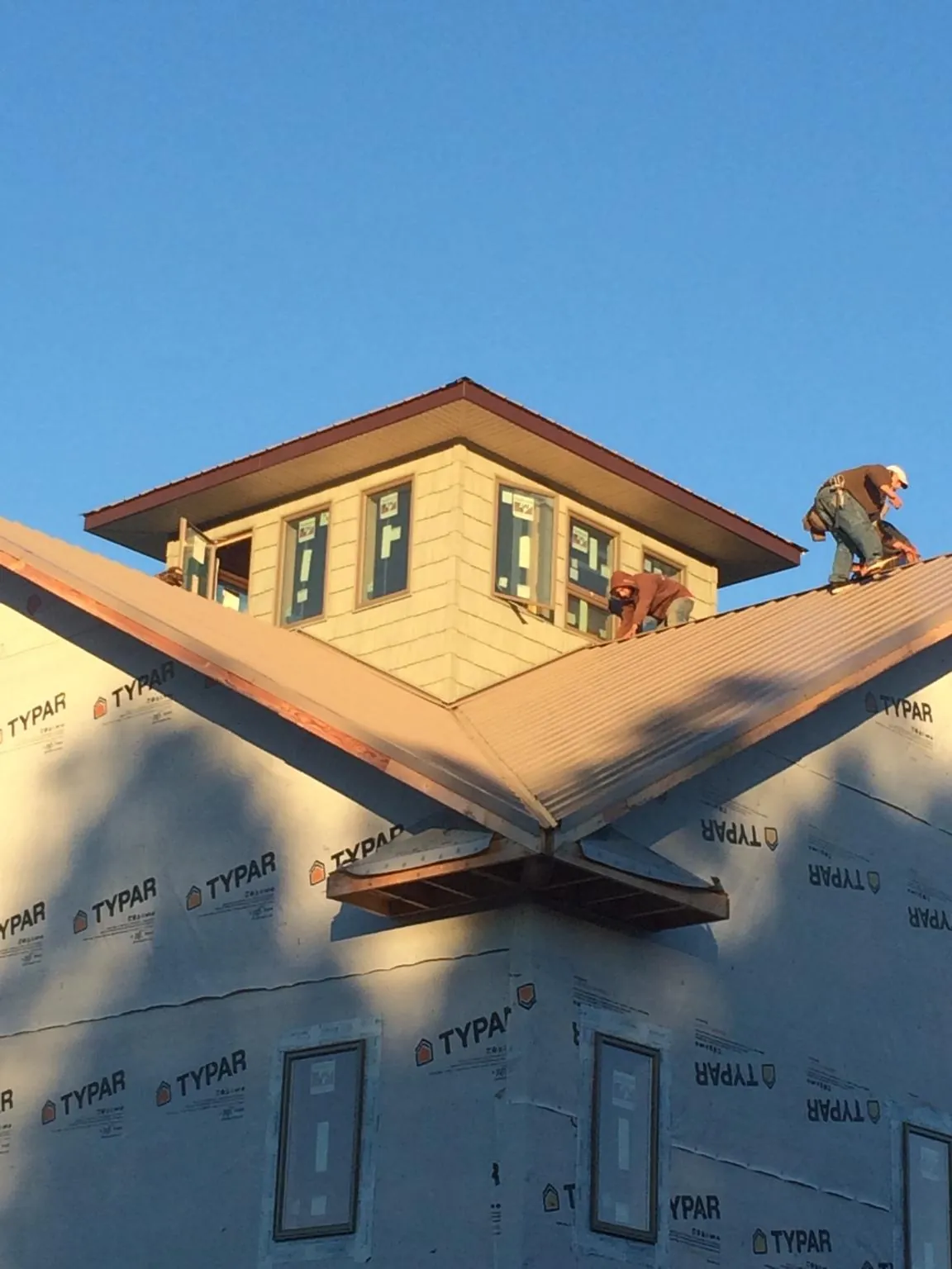 Roofers working around a rooftop cupola on a new metal roof at sunset — Roof Waterproofing in Penhook by Roofing Brothers